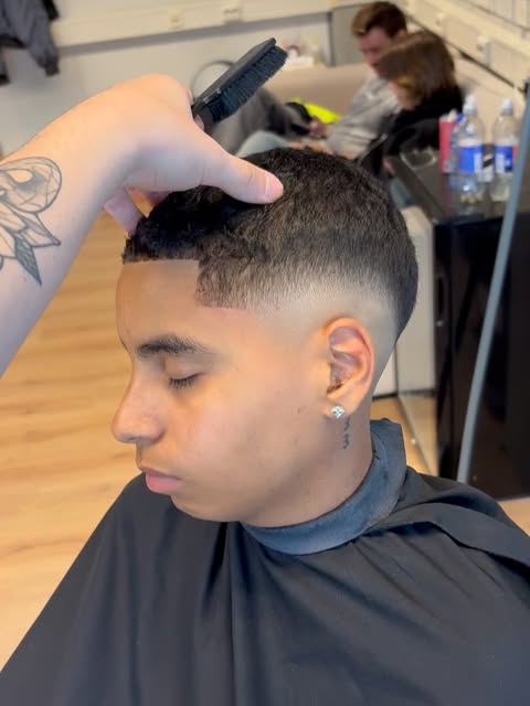 Fade in de maak, de barber werkt met kam en tondeuse